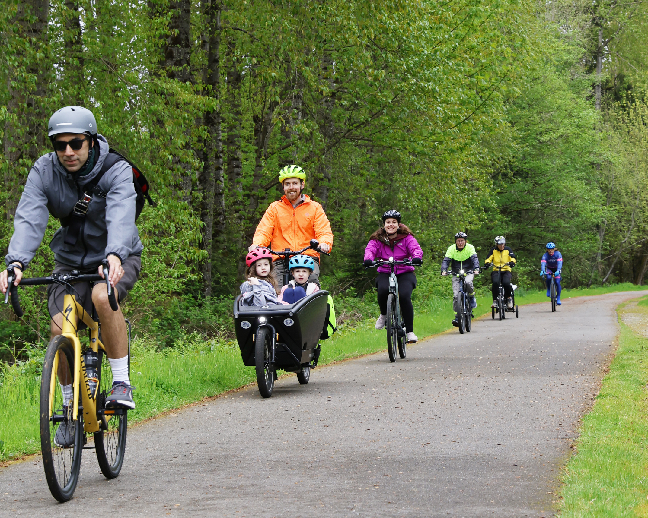 A group of bicyclists travel down a paved bike path